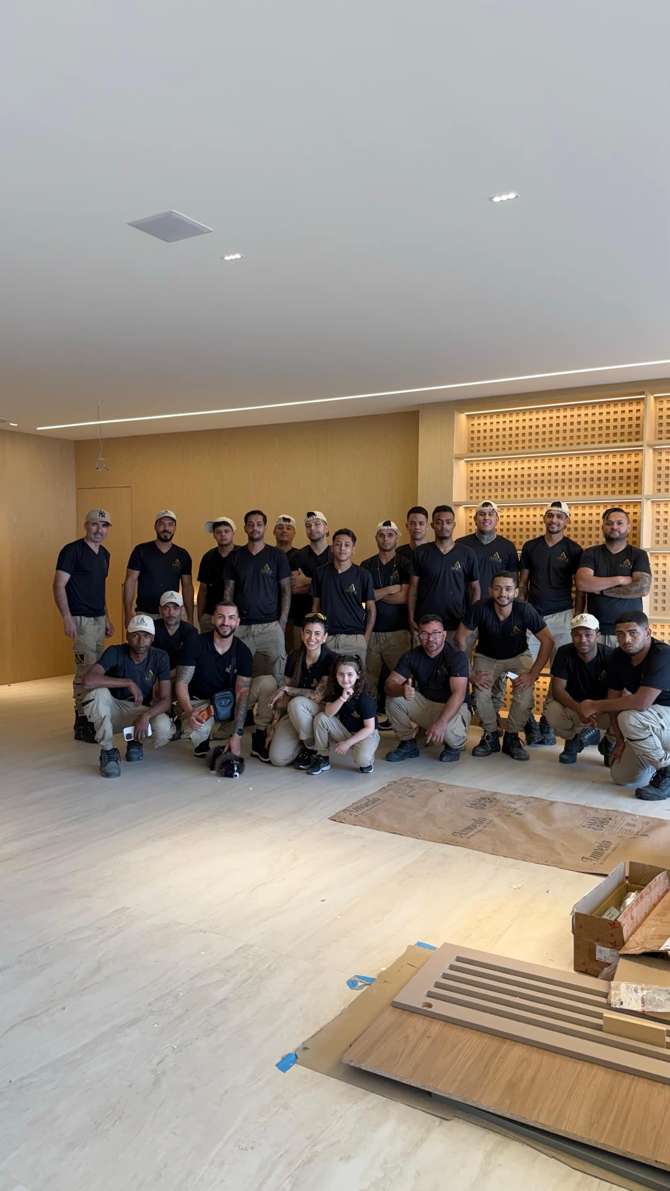 Equipe da Ápice Montagem, mais de vinte montadores de uniforme preto e bege, reunida num apartamento de alto padrão recém-montado